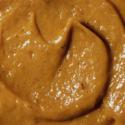 Close-up image of organic pumpkin facial mask with visible texture and slight shimmer.